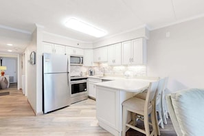 A modern kitchen with white cabinetry, stainless steel appliances, and a central island. - Marigot Beach 1206 (Ocean City)