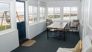 Une pièce comprenant une table à manger, des chaises, un canapé et de grandes fenêtres donnant sur la plage.