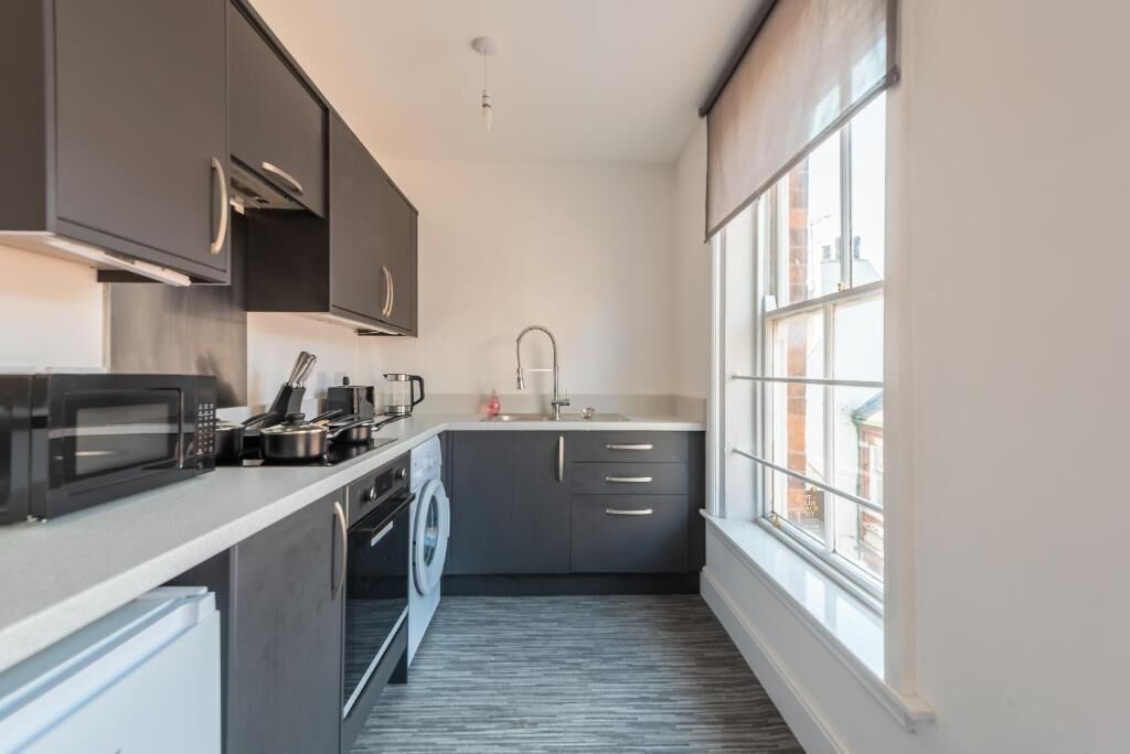 A compact kitchen with a microwave, kettle, and sink.