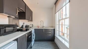 A compact kitchen with a microwave, kettle, and sink.