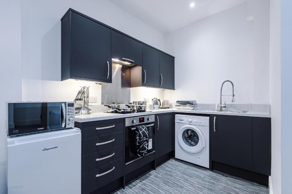 A modern kitchen with a built-in microwave, oven, and washing machine.