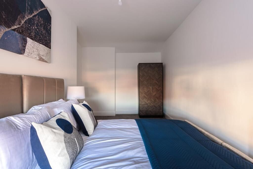 Une chambre d’hôtel moderne avec un grand lit, une table de chevet, une lampe et une œuvre d’art accrochée au mur.