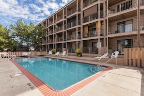A multi-story building with a swimming pool, outdoor seating, and a fenced area. - Lovely bayside condo with wading pool, balcony, beach access, W/D, & central AC (Ocean City)