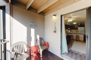 A balcony with two chairs, a wall sign, and a view into a kitchen area. - Lovely bayside condo with wading pool, balcony, beach access, W/D, & central AC (Ocean City)