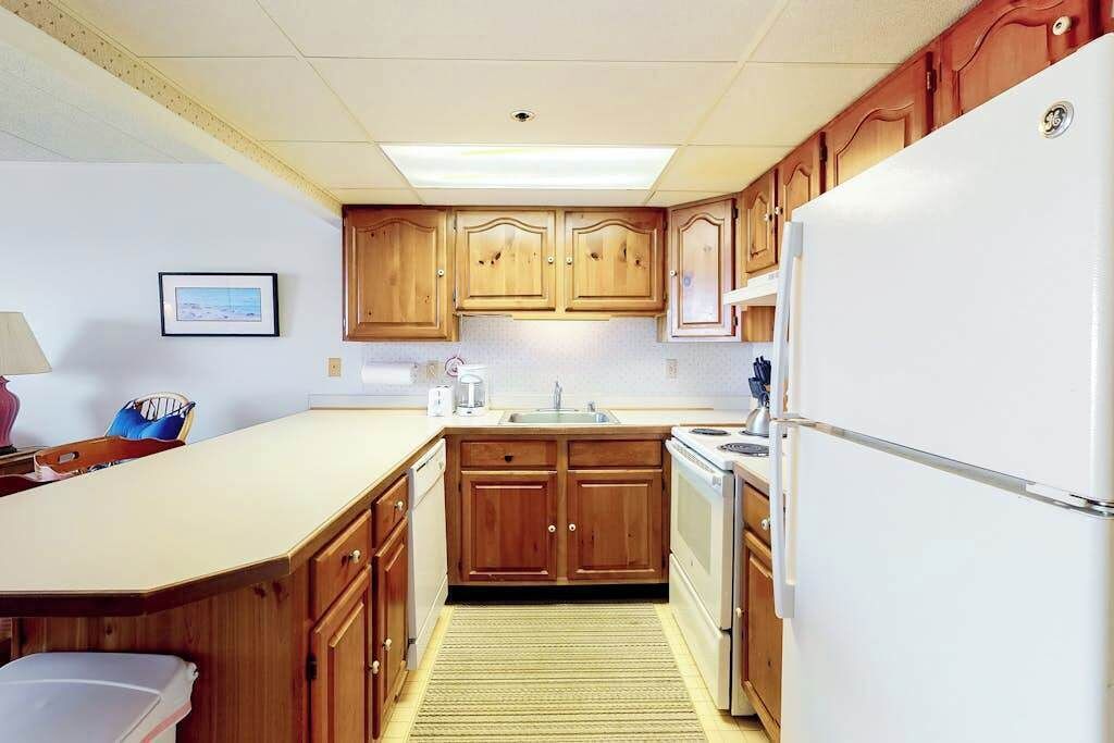 A compact kitchen with wooden cabinets, a white refrigerator, and a small sink.