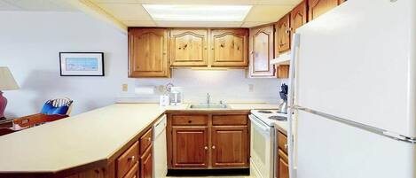 A compact kitchen with wooden cabinets, a white refrigerator, and a small sink.