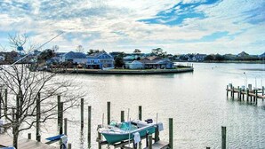 A waterfront property with docked boats, a pier, and houses in the background. - Waterfront condo with pool, balcony, fireplace, central AC, & washer/dryer (Ocean City)