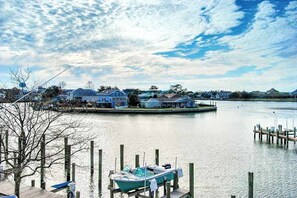 A waterfront property with docked boats, a pier, and houses in the background. - Waterfront condo with pool, balcony, fireplace, central AC, & washer/dryer (Ocean City)