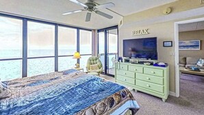 Een slaapkamer met een bed, een televisie, een dressoir en uitzicht op de oceaan.