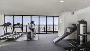 Een sportschool met loopbanden, een hometrainer en een krachtapparaat, met grote ramen met uitzicht.