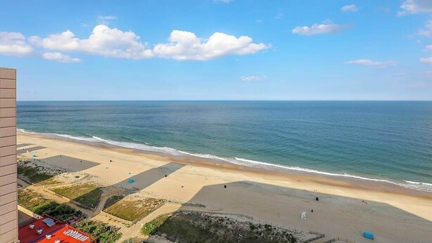 Uitzicht op het strand vanaf een balkon, met heldere lucht en een rustige zee.