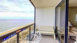 Een balkon met uitzicht op zee, een witte stoel, een bank en een 'ROOKVRIJ' bord.