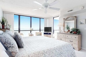 A bedroom with a large bed, a TV, a dresser, and a view of the ocean. - Classic beachfront condo with pools, beach bar, tennis & AC (Ocean City)