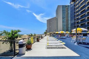 Eine Dachterrasse mit Liegestühlen, Sonnenschirmen und Topfpflanzen.
