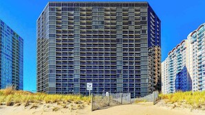 Ein Hochhaus mit einer rasterartigen Fassade, umgeben von ähnlichen Gebäuden.