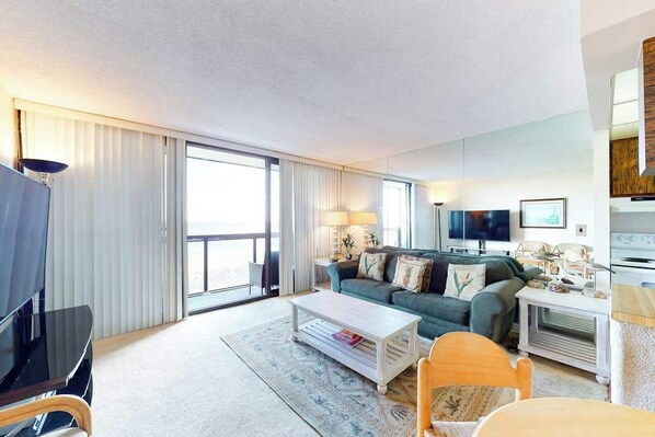 Et moderne hotelværelse med sofa, fjernsyn, sofabord og et spiseområde.