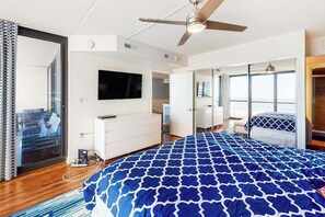 Ein Schlafzimmer mit Bett, Deckenventilator, Fernseher, Kleiderschrank und einer Schiebetür.