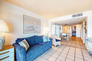 A living room with a sofa, a chair, a table, and a painting on the wall. - Fountainhead Towers 1206 (Ocean City)