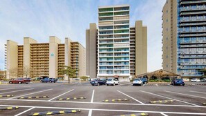 Un parking rempli de voitures, un bâtiment sur lequel on peut lire l’inscription « ENGELBORN », et plusieurs immeubles de grande hauteur en arrière-plan.