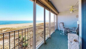 A balcony with a view of the beach, a table with chairs, and a ceiling fan. - English Towers 205 (Ocean City)