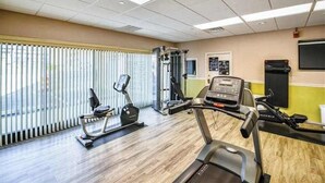 A gym with cardio machines, a weight bench, and a wall-mounted TV. - English Towers 205 (Ocean City)
