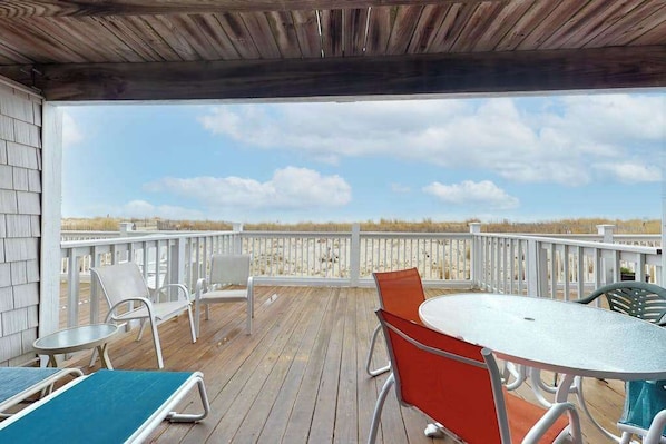 A covered outdoor deck with a table and chairs, a view of the beach, and a wooden ceiling. - Multi-level oceanfront townhouse w/deck, water views, central AC, washer/dryer (Ocean City)