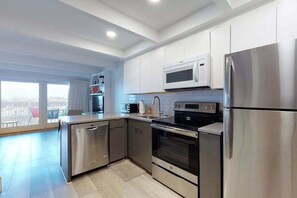 A modern kitchen with stainless steel appliances, a microwave, and a dishwasher. - Multi-level oceanfront townhouse w/deck, water views, central AC, washer/dryer (Ocean City)