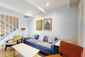 A modern living room with a sofa, chairs, a table, and a staircase. - Multi-level oceanfront townhouse w/deck, water views, central AC, washer/dryer (Ocean City)