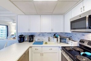 A modern kitchen with white cabinets, a microwave, a stove, a toaster, and a coffee maker. - Family-Friendly Condo w/Private Balcony, Washer/Dryer, Cable, and Central A/C (Ocean City)