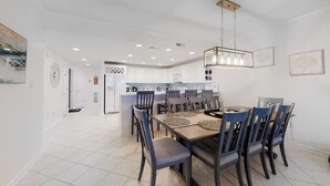 Un comedor moderno con una mesa rectangular, varias sillas e iluminación colgante.