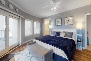 Ein Schlafzimmer mit einem großen Bett, einem Deckenventilator und Blick ins Freie.