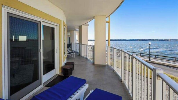 Un balcón con vista al mar, una puerta corrediza de vidrio y una silla.