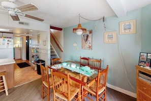 A dining area with a glass table, wooden chairs, a ceiling fan, and a staircase. - Comfy, Oceanside Townhouse w/Private Washer/Dryer, Free WiFi, & Balcony (Ocean City)