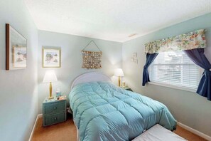 A bedroom with a bed, two bedside tables, a wall hanging, and a window with curtains. - Comfy, Oceanside Townhouse w/Private Washer/Dryer, Free WiFi, & Balcony (Ocean City)