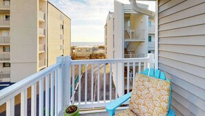 A balcony with a white railing, a blue chair, and a potted plant. - Cinnamon Teal 10 (Ocean City)