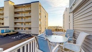Ett hotell med en parkeringsplats, en uteservering med stolar och en byggnad med flera balkonger.