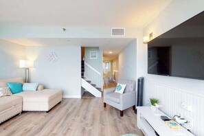 Ein Wohnzimmer mit einer Couch, einem Sessel und einem Flachbildfernseher.