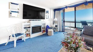 Hotelkamer met een grote televisie, een open haard, een bank en een balkon met uitzicht.