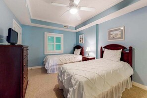 A bedroom with two beds, a ceiling fan, a dresser, and a television. - Coral Seas 201 (Ocean City)