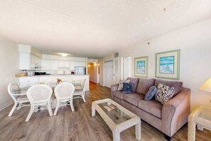 Ein Wohnzimmer mit Sofa, Couchtisch und Essbereich mit Stühlen.