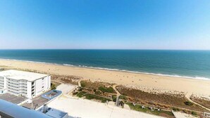 A coastal view with a beach, a parking area, and a building with multiple floors. - Carousel 1707 (Ocean City)