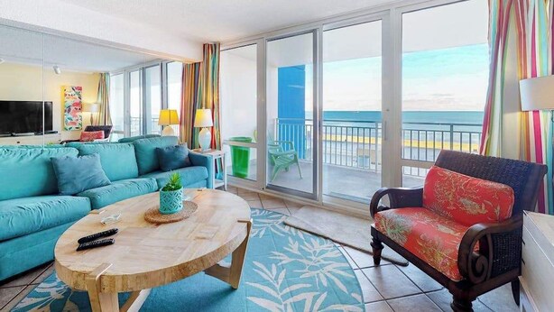 A room with a sofa, a chair, a round table, and a TV.