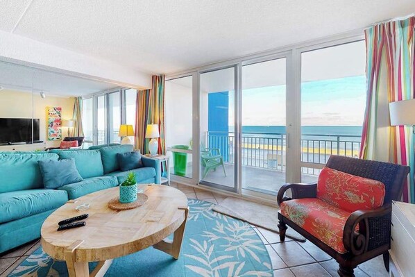 A room with a sofa, a chair, a round table, and a TV.