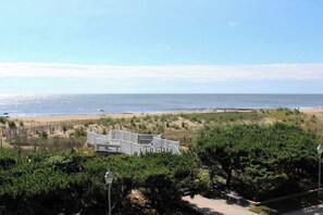 Ein Hotel direkt am Strand mit einem weißen Gebäude, Sandstrand und üppiger Vegetation.