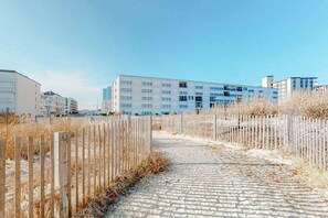 Un camí de llambordes que condueix a un edifici modern amb diverses plantes i balcons.