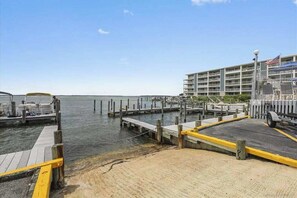 A waterfront hotel with a dock, a parking area, and a building with multiple floors. - Bradley On The Bay 130G (Ocean City)