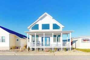 A white two-story house with a balcony, a front porch, and a clear blue sky. - Atlantic Blvd 13314 (Ocean City)