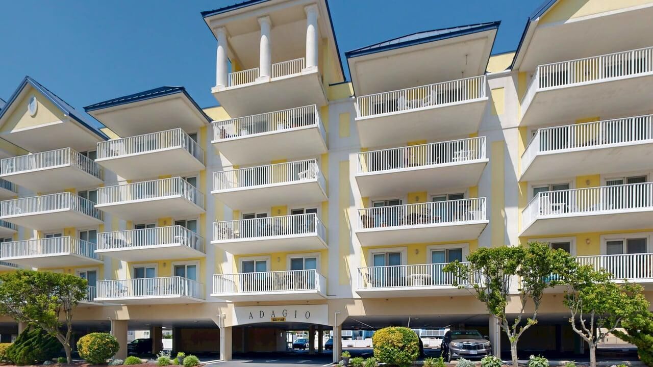 Un hôtel à plusieurs étages doté de balcons, d’un parking couvert et offrant une vue sur un ciel dégagé.