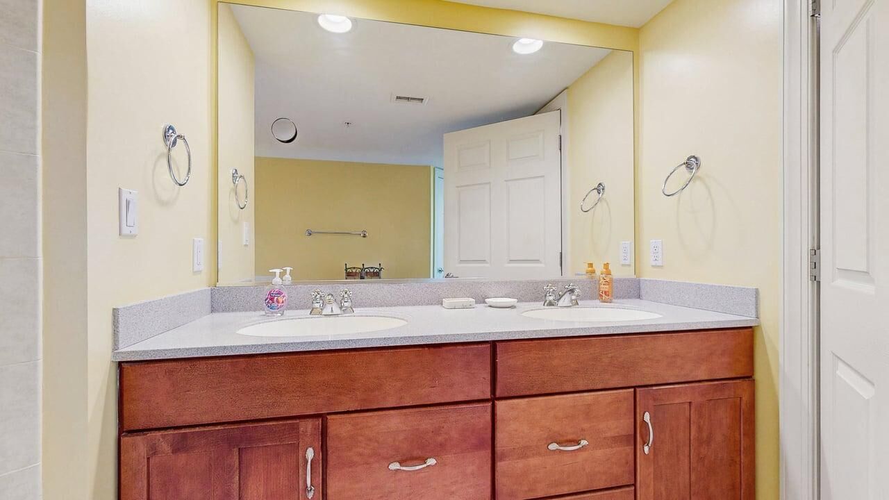 Un baño con dos lavamanos, armarios de madera, un espejo y una puerta.