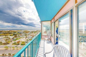 A balcony with a view of a residential area and the sea. - Bright coastal condo with pool access, side views of the ocean, balcony & W/D (Ocean City)